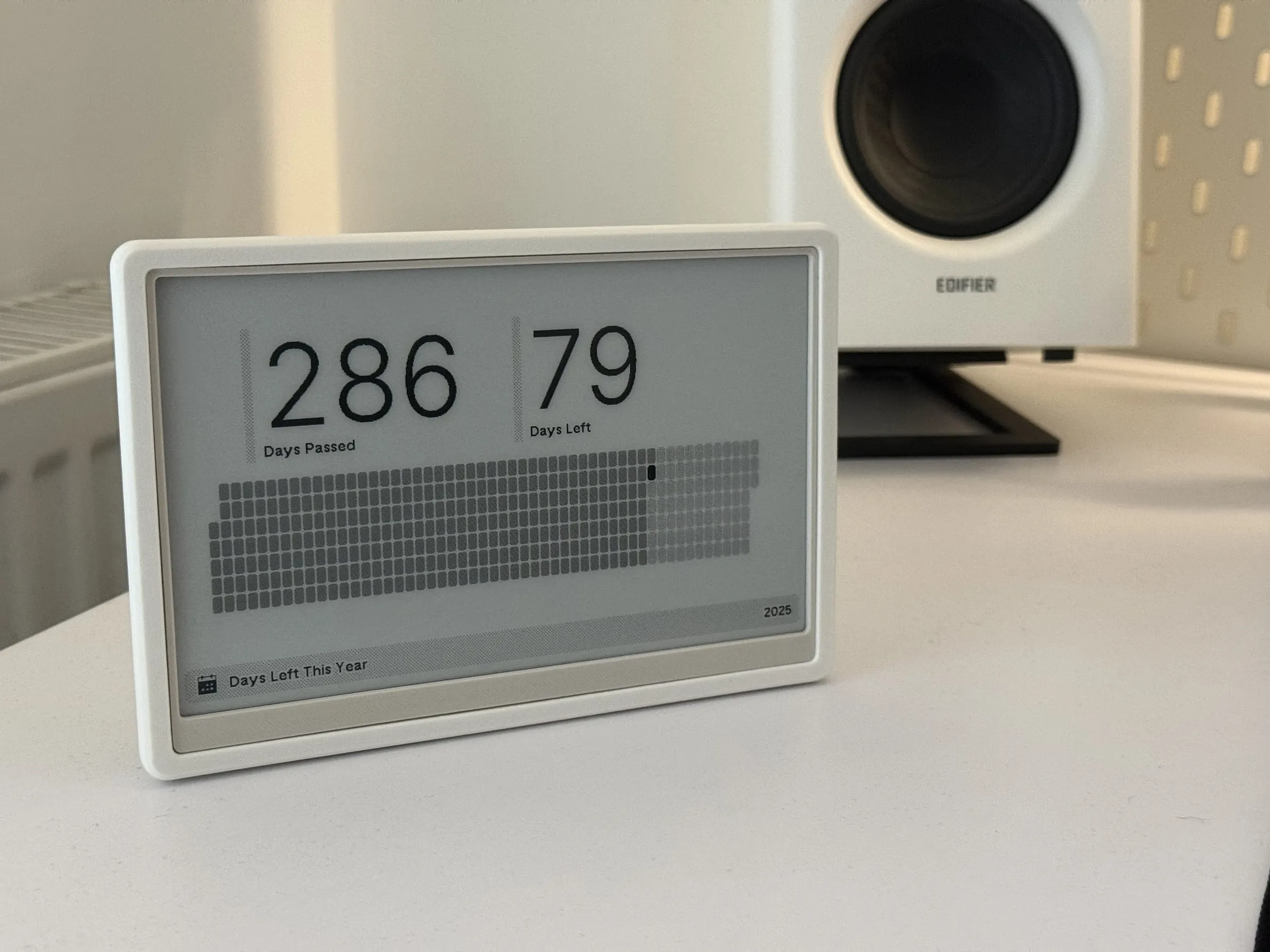 White 3D printed case standing on a desk at an angle, the e-ink screen showing how many days are left this year