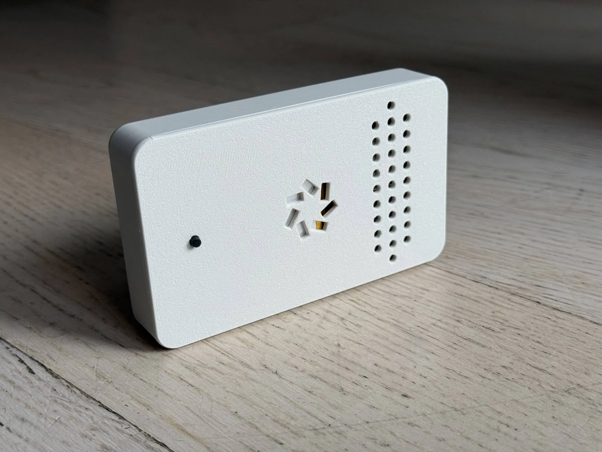 The back of the case: a plain white panel with a small black button, a cut-out logo and a grid of vent holes