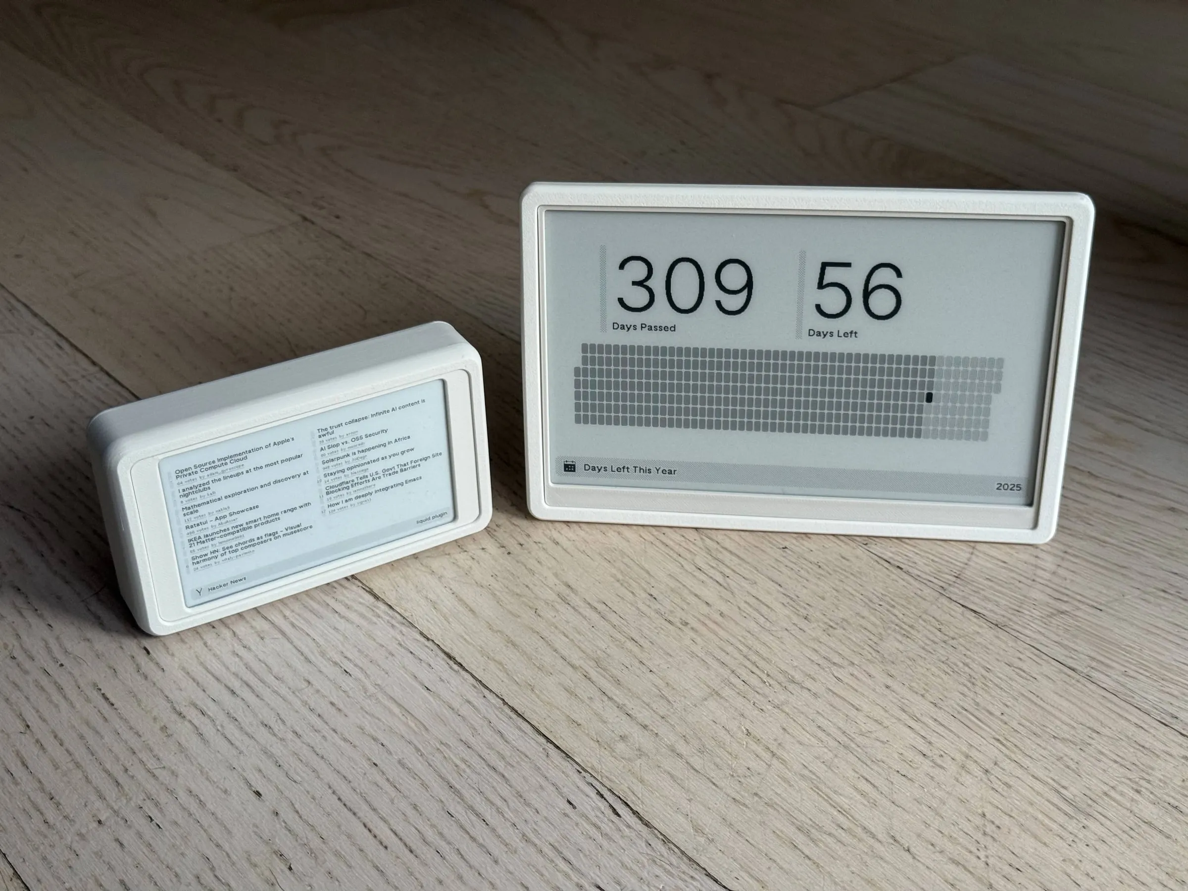 The mini next to a much larger e-ink display in a similar white case, which shows 309 days passed and 56 days left