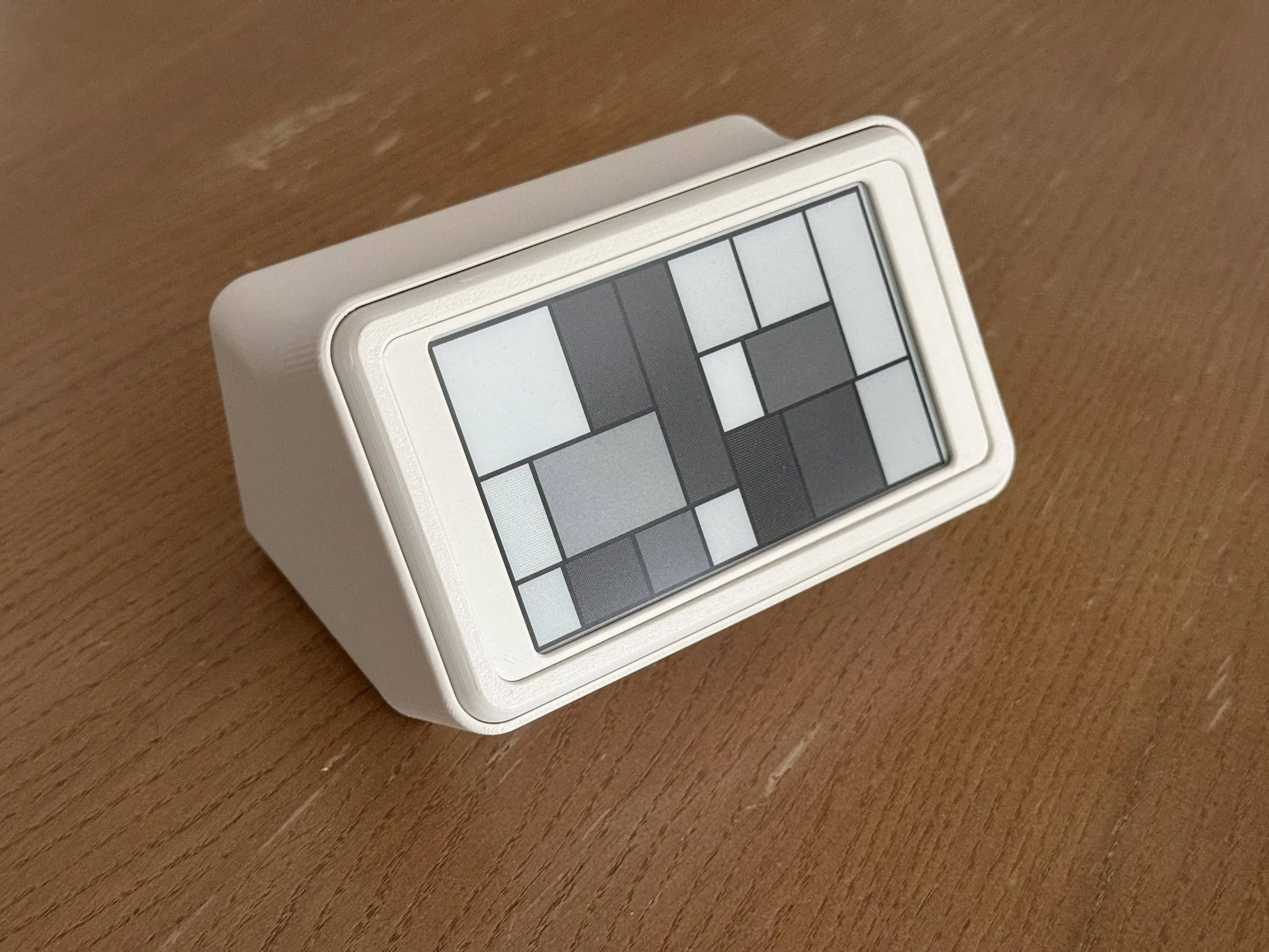 The mini in its stand, standing more upright, the screen showing a pattern of grey rectangles