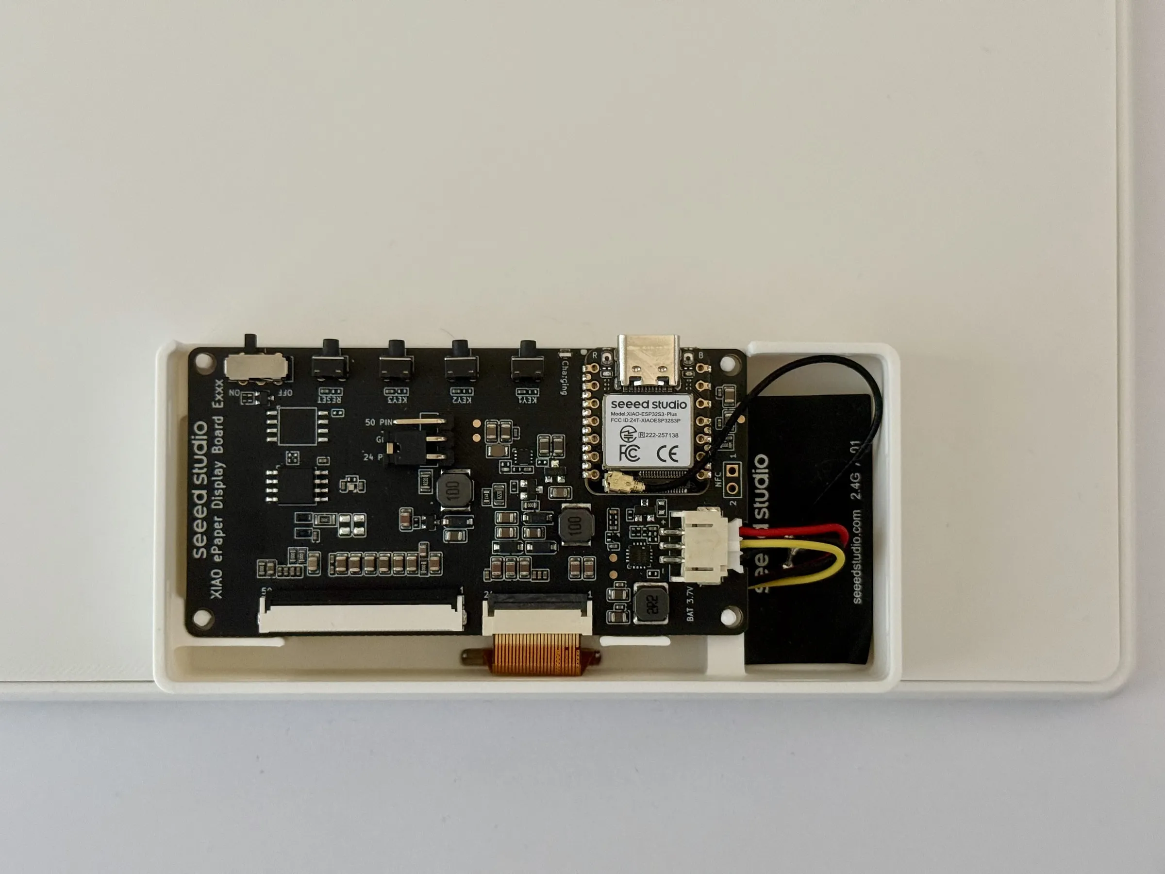 The box on the back with the cover off: the Seeed Studio XIAO ePaper Display Board, the battery cable and the flat WiFi antenna